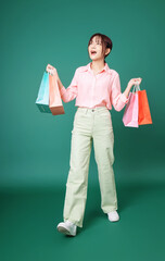 Wall Mural - Image of young Asian girl holding shopping bag on background