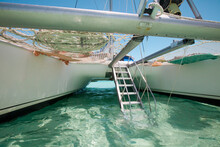 A Drop-down Aluminum Staircase Leads Up To The Deck Of A Catamaran Boat.