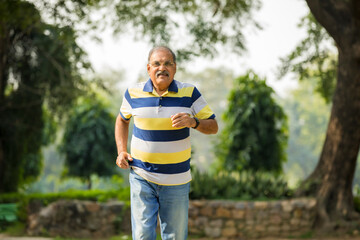 Wall Mural - Indian old man running or jogging at park