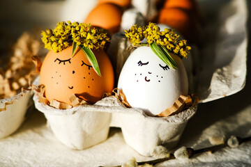 Wall Mural - Easter eggs with a funny face and a wreath of flowers in an egg cage. Side view, close-up. Easter concept.