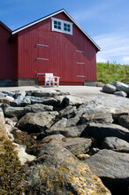 Red Wooden Boathouse On The West Coast Of Norway With Empty Chair