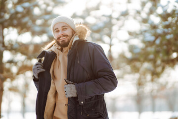 Wall Mural - Young man in snowy winter forest. People, lifestyle, relaxation and vacations concept.