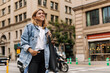 © Look! - Attractive young woman walking in the city and look with smile away. Caucasian blonde wearing blue jeans jacket at the street. Lifestyle concept