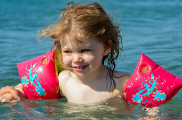 Wall Mural - Little girl splashing in the crystal clear water in a lagoon