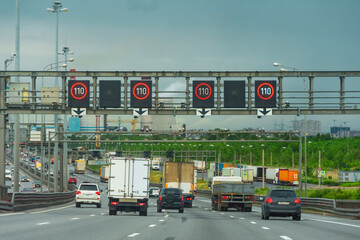 Wall Mural - Highway suburban bypass highway loaded with high speed car traffic, urban landscape in the distance.