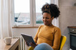 © cherryandbees - A mixed race woman enjoys her morning coffee and uses a tablet