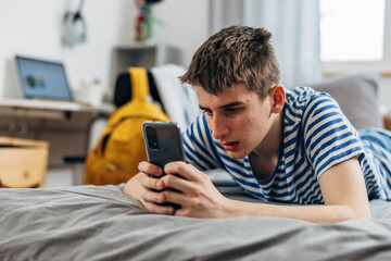 Teenage boy is surfing on the internet using his phone