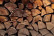 A woodpile with stacked firewood, for a fireplace and preparation for winter, background with firewood, stacked chopped wood close up texture.