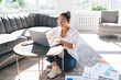 © BullRun - Woman working on netbook in living room