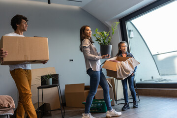 Wall Mural - Mixed race family moving into their new home. They're carrying cardboard full of their accessories.	