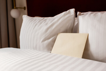 Sticker - yellow envelope on white and clean bedding in hotel room.