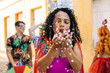 © kleberpicui - Brazilian Carnival. Young woman enjoying the carnival party blowing confetti
