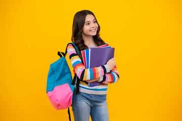 Schoolchild, teenage student girl hold book on yellow isolated studio background. School and education concept. Back to school. Happy teenager, positive and smiling emotions of teen girl.