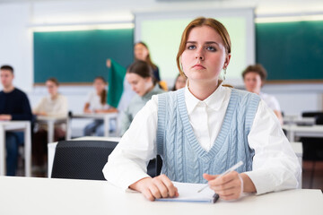 Wall Mural - Group of school teenagers with pens and notebooks studying in classroom with teacher