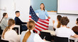 © JackF - Geography lesson in school class - teacher talks about United States of America, holding a flag in his hands