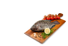 Raw Fish Tilapia With Spices And Herbs Ingredients For Cooking, Lemon And Tomatoes On Wooden Cutting Board Isolated On White Background With Copy Space