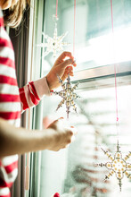 Child Decorating And Hanging Christmas Stars On Window