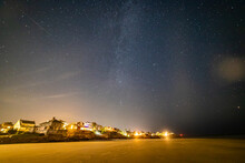 Meteors Shower And Milky Way In The Night Sky Above Beach Houses.