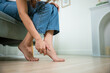© sorapop - Asian young woman sitting on sofa holding her feet and stretch muscles have symptoms feeling pain, beautiful female problems with foot at home, painful ankle injury, Health care and medical concept