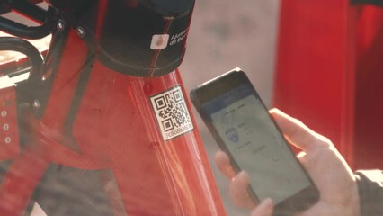 Hands using smartphone scanning the QR code of shared bike in city