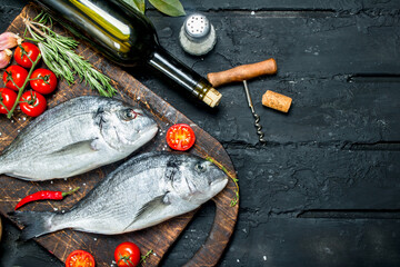 Wall Mural - Raw sea fish dorado with herbs, spices and a bottle of white wine.