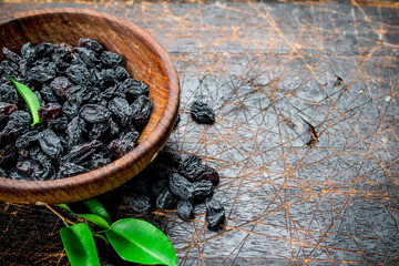 Canvas Print - Raisins in a bowl with green leaves.