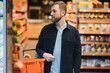 Portrait of smiling man walking with his trolley on aisle at supermarket.