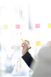 © David - Young creative business Asian woman standing with her colleagues writing new ideas on sticky notes over glass wall, business marketing strategy or User experience ux ui concept.