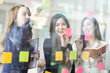 © David - Young creative business Asian woman standing with her colleagues writing new ideas on sticky notes over glass wall, business marketing strategy or User experience ux ui concept.