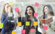 © David - Young creative business Asian woman standing with her colleagues writing new ideas on sticky notes over glass wall, business marketing strategy or User experience ux ui concept.