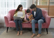 © Verin - young parent spend their free time playing with little daughter on sofa in living room, mother using laptop, father talking to kid and playing tablet together