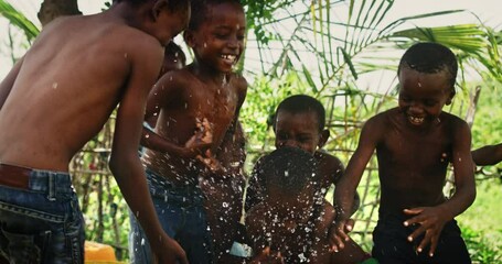 Wall Mural - A Group Of African Children, Laughing and Playing with Water in Rural Area. Black Kids Celebrating Life with Joy. Camera Captures Beauty Of Childhood, Innocence and Purity of Live in Village