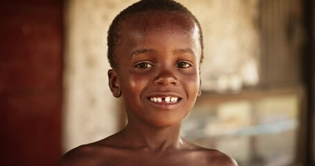 Wall Mural - Portrait of a Smiling African Kid in a Rural Area Laughing and Looking at the Camera. Little Face Full Of Joy and Life After Having Fun Playing with Water and Getting Refreshed in Summer Hot Weather