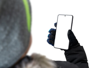 Fototapete - Guy in a jacket with a cap and gloves is holding a mobile phone. The background and the phone's display are isolated in white for a mockup, presentation of the design of an app or website