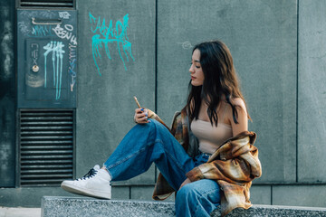 Sticker - young girl sitting with phone on the street