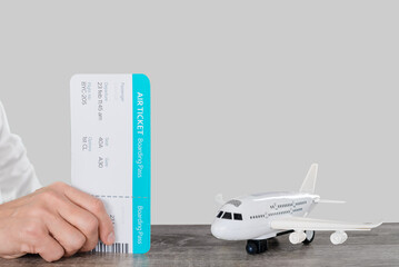 Wall Mural - Man traveler holding airline boarding pass while waiting plane in the studio on a light gray background