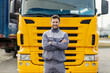 Portrait of a confident truck driver smiling at the camera while standing outdoors in front of the lorry.