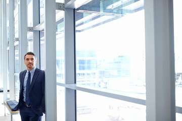 Vision, mindset and window with a business man at work, standing in his office while thinking of an idea. Corporate, growth and future with a male employee leaning against a glass wall while working