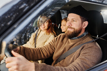 Happy bearded man driving car, he taking his family on winter vacation