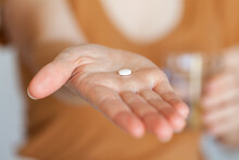Person Holding Oxycodone Pain-relief Tablet And Glass Of Water