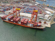 © Austockphoto - Aerial view of a large cargo ship getting loaded with containers by cranes at a port