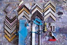 Overhead View Of Picture Frame Corners With Work Tools On Table In Workshop