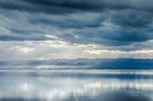 Idyllic View Of Lake By Mountains Against Stormy Clouds