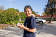 © Austockphoto - Medical nurse walking through a car park holding her phone smiling
