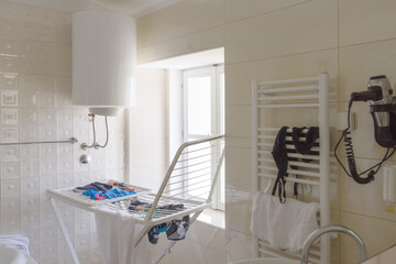 Cluttered bathroom with clothes on drying rack