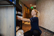 © Dusan Petkovic - A happy maid is taking clean towels from a rack in a hotel lobby.