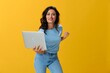 © SHOTPRIME STUDIO - Woman freelancer with a laptop in her hands in a blue t-shirt and jeans on a yellow background smile signs gestures symbols, copy space, free background