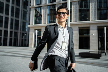 Wall Mural - A successful happy businessman going to the office in the afternoon in a business suit with a briefcase.