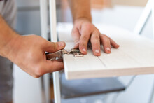 Worker Placing Concealed Hinge Into Wooden Wardrobe Door. Furniture Installation Concept.