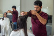 © Angela - Um cabeleireiro separando uma mecha de cabelo de uma cliente para cortar. Reflexo da ação no espelho.